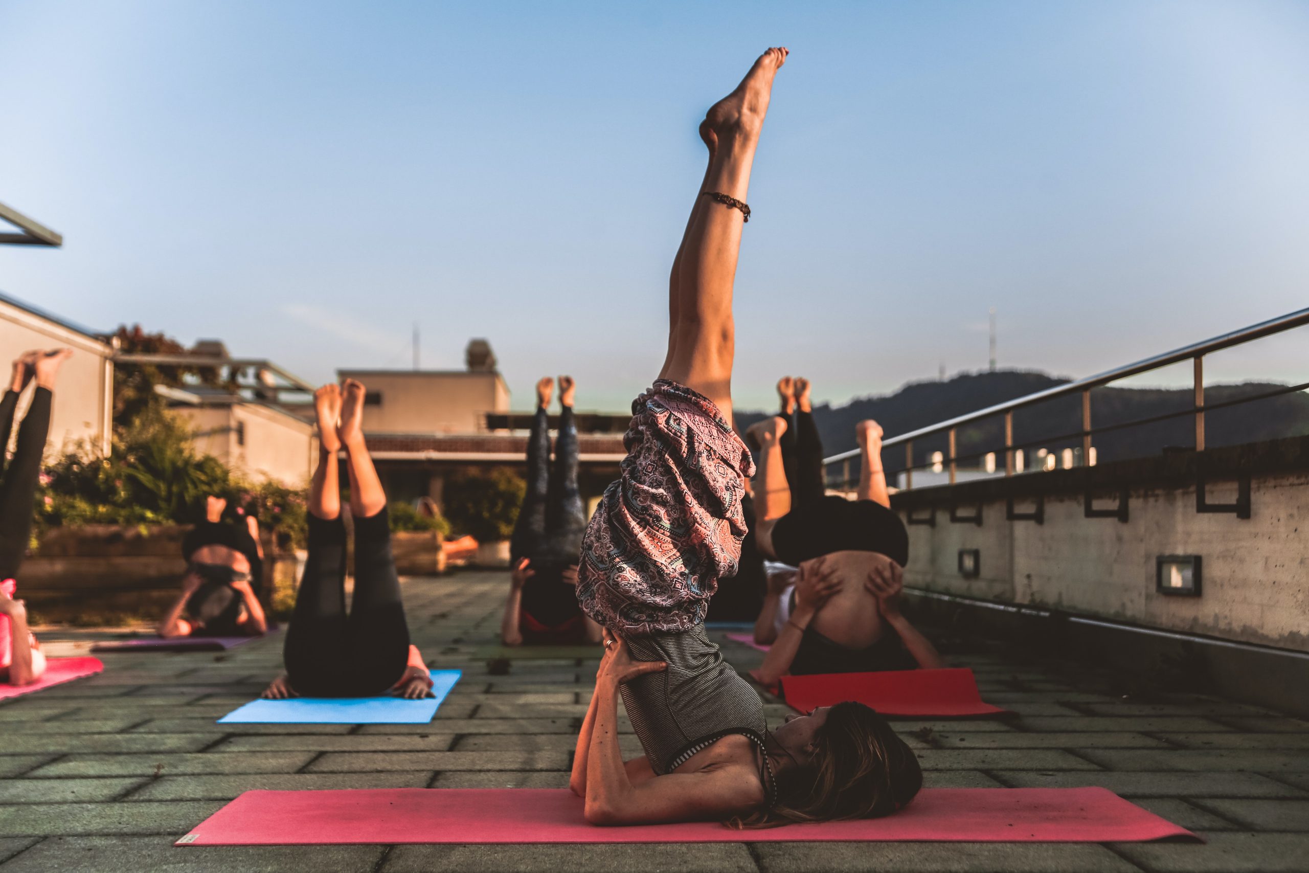 Group of people practicing yoga on a rooftop in the evening